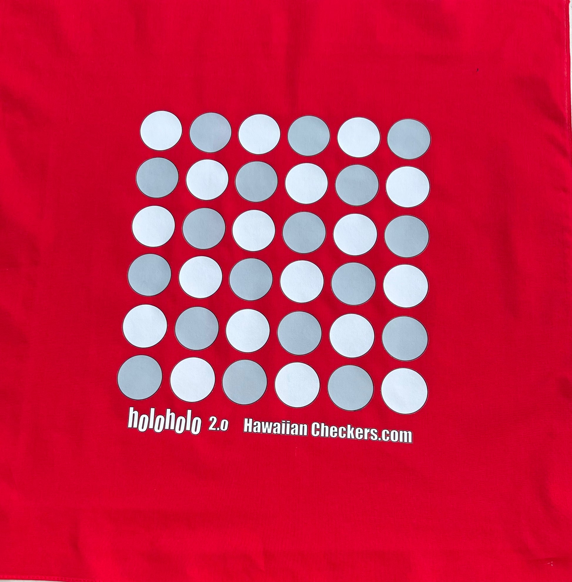 Red fabric with a pattern of white and gray circles and text on a red background for playing a hawaiian strategy game called konane.